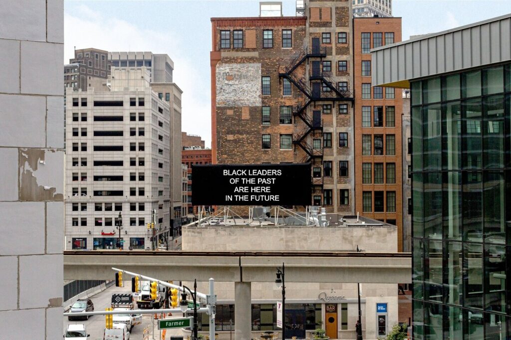 Photo of buildings with a billboard that reads "Black Leaders of the Past are here in the Future"
